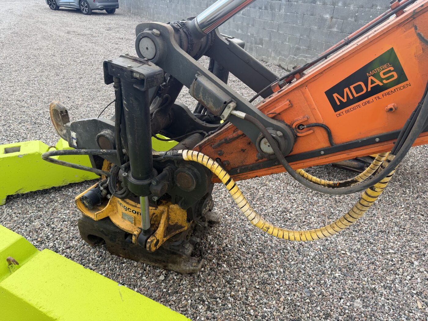 Nærbillede af Engcon tiltrotator og hurtigskifte på Doosan DX 300 LC, hvilende på en grøn betonklods