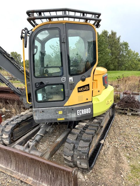 Volvo ECR88D set skråt fra dørsiden med kabine, beskyttelsesgitter over taget, MDAS-mærkat, ECR88D-decal på hækken og dozerbladet forrest